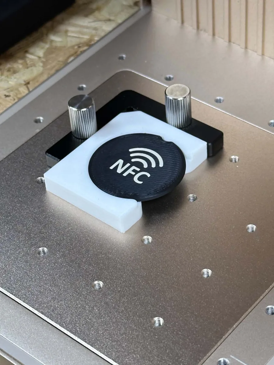 Jeton NFC noir maintenu par un gabarit blanc imprimé en 3D sur le plateau du graveur laser