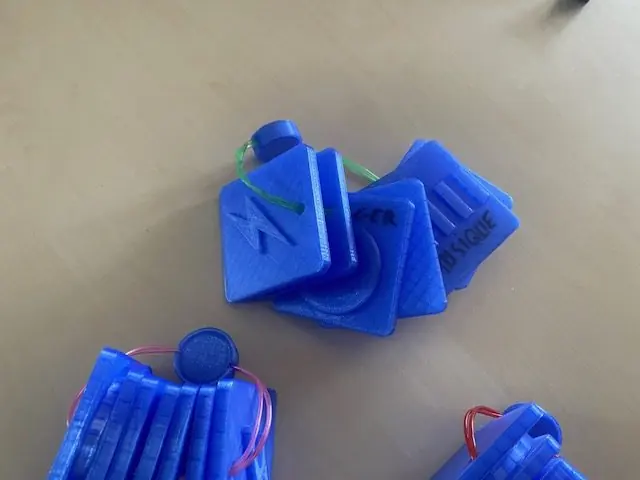 Jeux de plaques carrées bleues à motifs en relief, reliées par un cordon et annotées au feutre